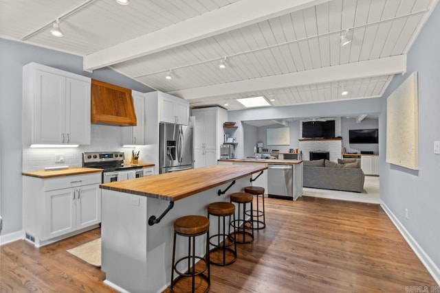 kitchen with white cabinets, wood counters, a kitchen breakfast bar, and stainless steel appliances