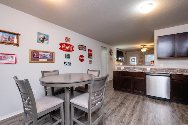 dining space featuring a textured ceiling, ceiling fan, light wood-type flooring, and sink