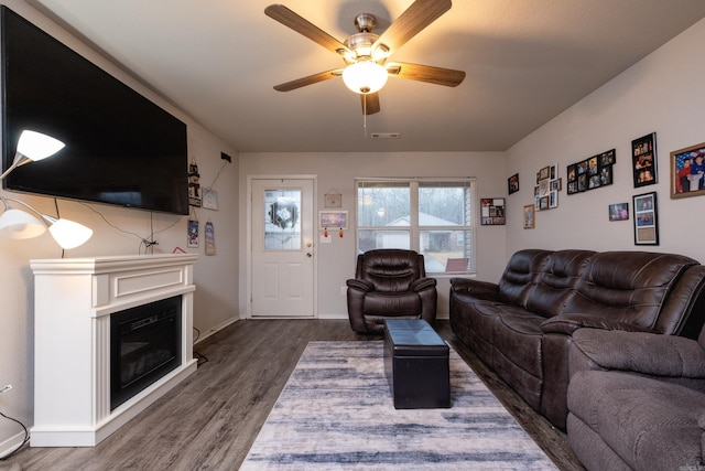 living room with ceiling fan and dark wood-type flooring