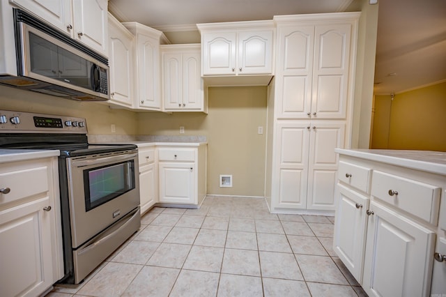 kitchen with white cabinets, light tile patterned floors, crown molding, and appliances with stainless steel finishes