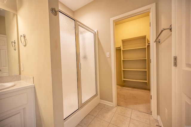 bathroom with tile patterned flooring, vanity, and walk in shower