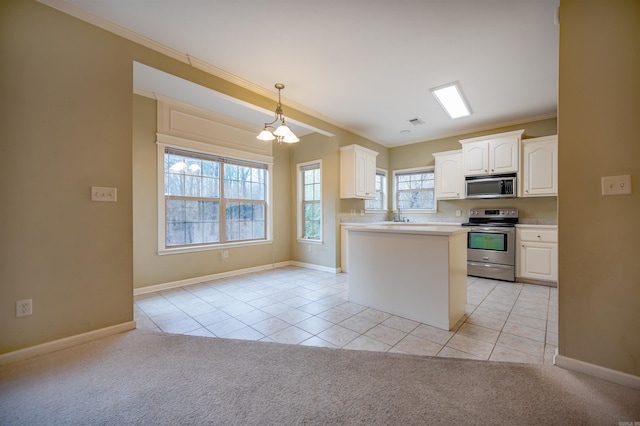 kitchen with white cabinets, appliances with stainless steel finishes, plenty of natural light, and light tile patterned flooring