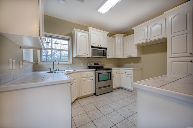 kitchen with sink, stainless steel appliances, tile countertops, crown molding, and white cabinets