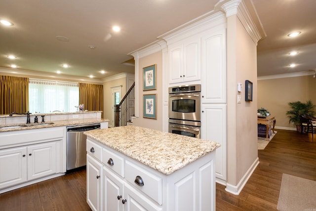 kitchen featuring appliances with stainless steel finishes, dark wood-type flooring, sink, a center island, and white cabinetry