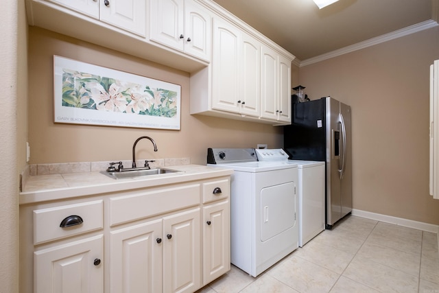 laundry area featuring washing machine and clothes dryer, sink, cabinets, and ornamental molding