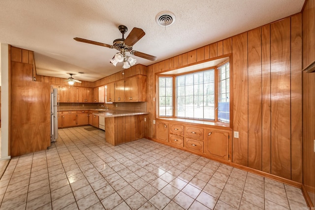 kitchen featuring ceiling fan, kitchen peninsula, a textured ceiling, and fridge