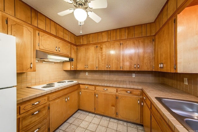 kitchen with decorative backsplash, tile counters, light tile patterned floors, and white appliances