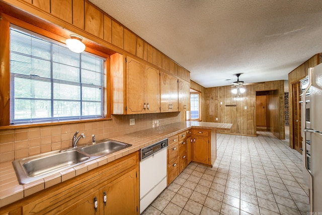 kitchen with tile countertops, white dishwasher, tasteful backsplash, and a healthy amount of sunlight