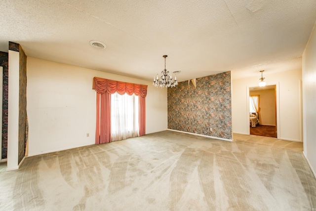 spare room featuring carpet, a chandelier, and a textured ceiling