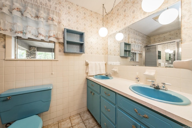 bathroom featuring tile patterned floors, a shower with door, vanity, and tile walls