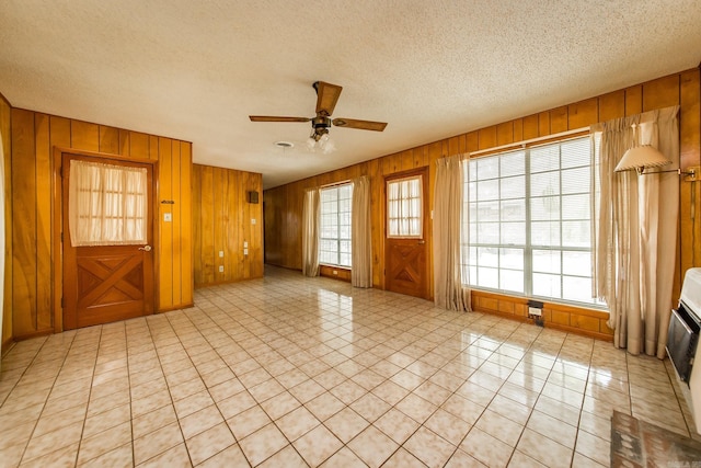 spare room featuring wood walls, ceiling fan, and a textured ceiling