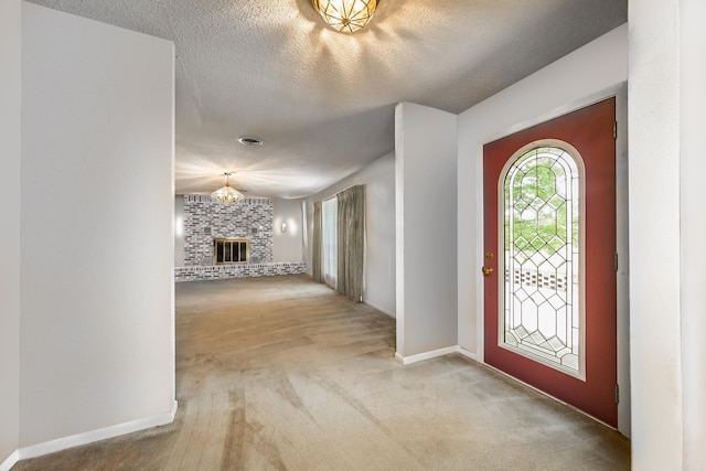 carpeted foyer entrance featuring a fireplace and a textured ceiling