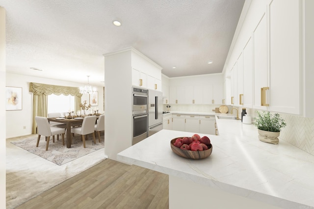 kitchen with sink, white cabinetry, tasteful backsplash, light hardwood / wood-style floors, and kitchen peninsula