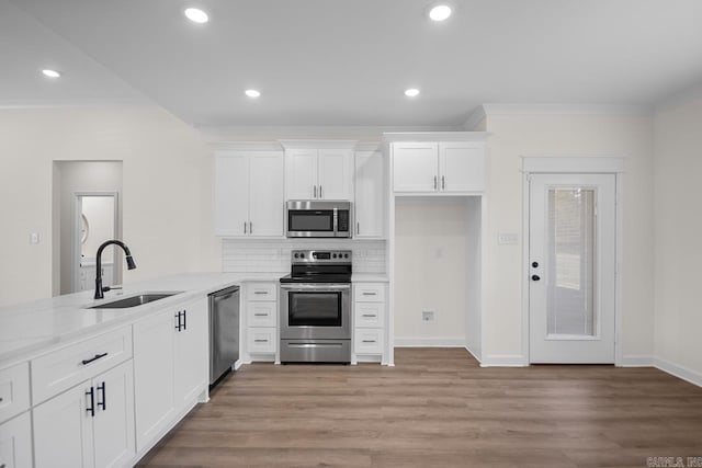 kitchen featuring sink, light stone counters, appliances with stainless steel finishes, white cabinets, and ornamental molding