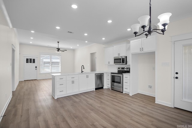 kitchen with ceiling fan with notable chandelier, kitchen peninsula, sink, and appliances with stainless steel finishes