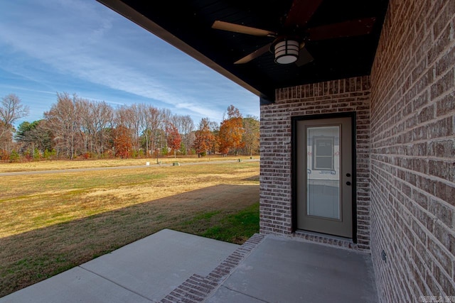 entrance to property with a lawn, a patio area, and ceiling fan