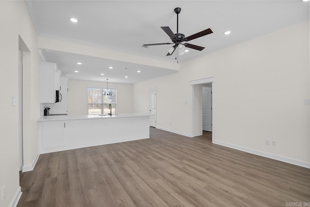 unfurnished living room with ceiling fan, sink, and light hardwood / wood-style flooring