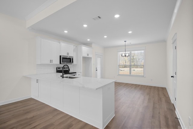 kitchen featuring white cabinetry, sink, hanging light fixtures, stainless steel appliances, and kitchen peninsula