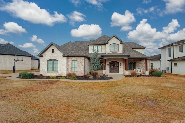 french provincial home with stone siding, french doors, roof with shingles, and a front lawn