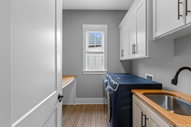 laundry room featuring cabinets, light wood-type flooring, sink, and washing machine and dryer