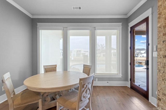 dining space with light wood-type flooring and crown molding