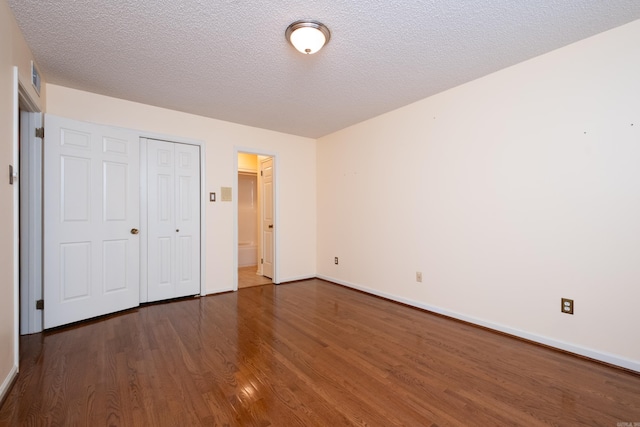 unfurnished bedroom with a textured ceiling, a closet, and dark hardwood / wood-style floors