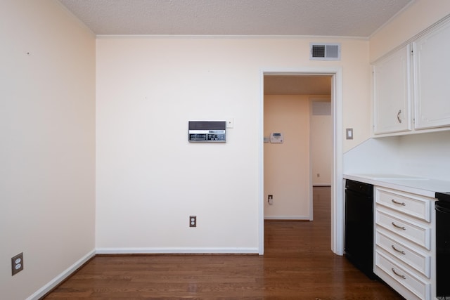 kitchen featuring white cabinetry, dark wood-type flooring, a textured ceiling, and ornamental molding