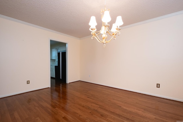 empty room with a textured ceiling, ornamental molding, dark wood-type flooring, and an inviting chandelier