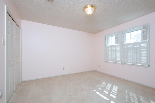 unfurnished bedroom featuring a closet, light colored carpet, and a textured ceiling