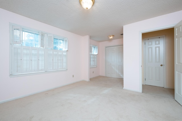 unfurnished bedroom with light colored carpet, a textured ceiling, and a closet