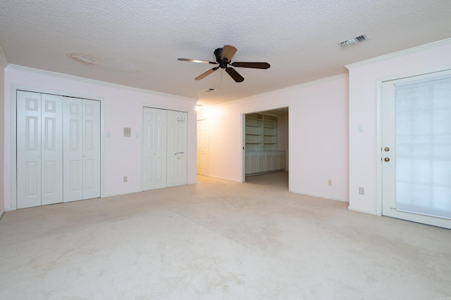 unfurnished bedroom with light carpet, ceiling fan, a textured ceiling, and ornamental molding