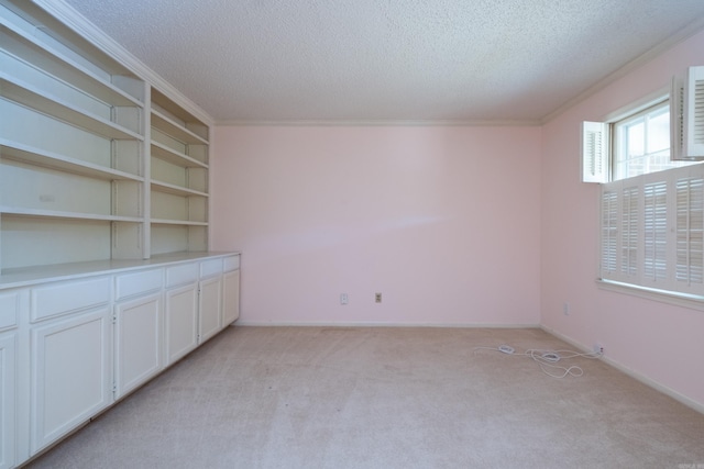 carpeted empty room featuring a textured ceiling and crown molding