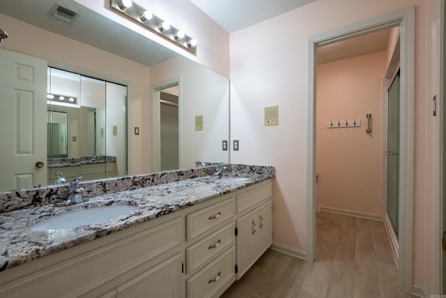 bathroom featuring vanity, a shower with shower door, a textured ceiling, and hardwood / wood-style flooring