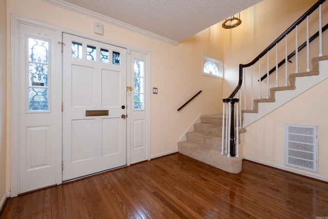 entrance foyer featuring crown molding, hardwood / wood-style floors, a healthy amount of sunlight, and a textured ceiling