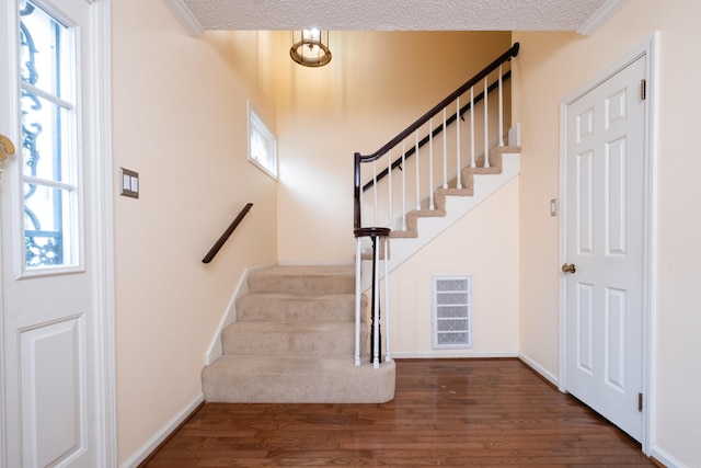 foyer entrance with a textured ceiling, dark hardwood / wood-style floors, and ornamental molding