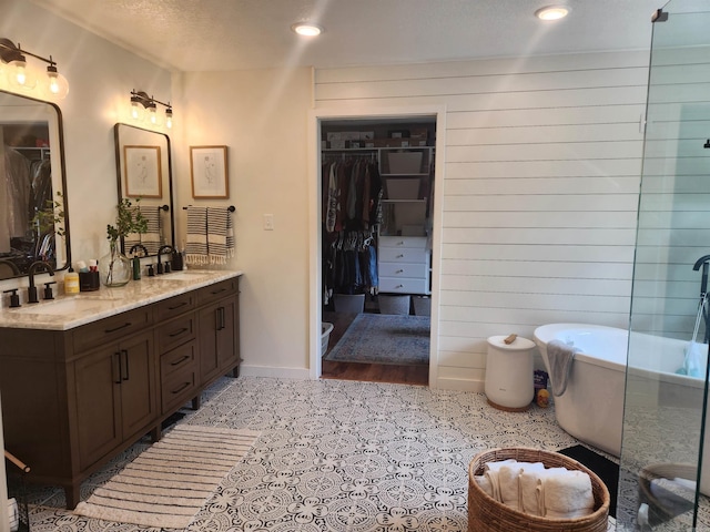 bathroom with a bathtub, a textured ceiling, vanity, hardwood / wood-style flooring, and wood walls