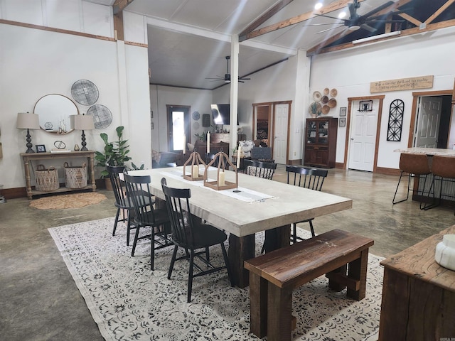 dining area with beam ceiling, ceiling fan, high vaulted ceiling, and concrete floors