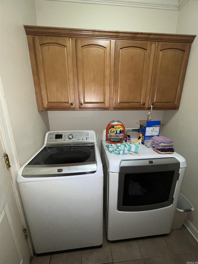 washroom featuring cabinets, washing machine and dryer, and light tile patterned floors