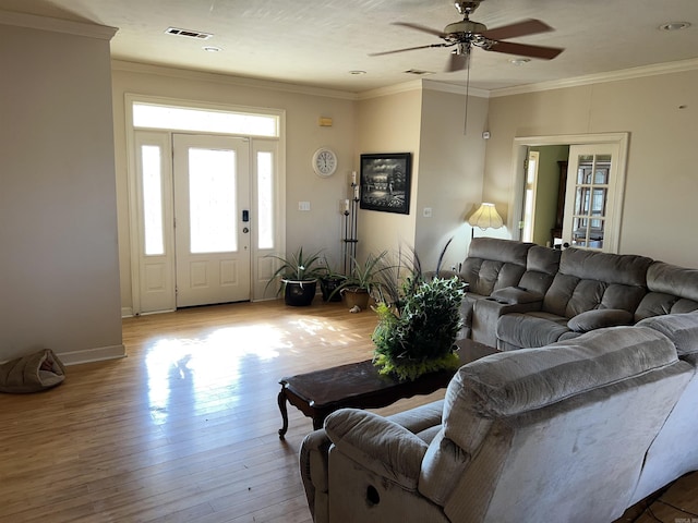 living room featuring ceiling fan, ornamental molding, and light wood-type flooring