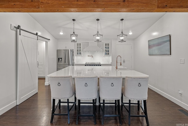 kitchen featuring white cabinets, decorative light fixtures, a barn door, a large island, and stainless steel appliances