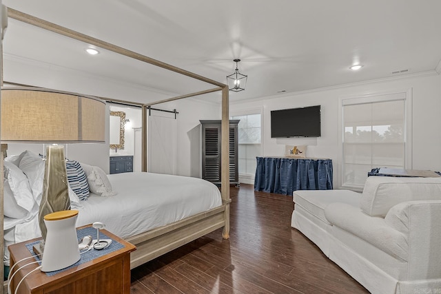 bedroom with a barn door, dark hardwood / wood-style floors, and crown molding