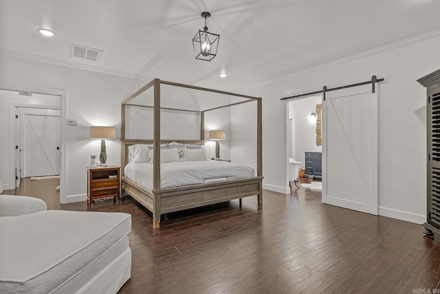 bedroom with ensuite bathroom, a barn door, ornamental molding, and dark wood-type flooring