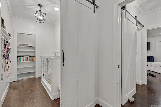 hallway with a chandelier, ornamental molding, a barn door, and dark wood-type flooring