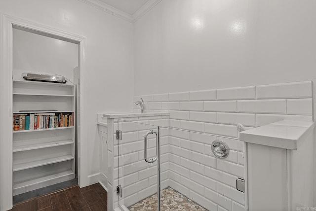 bathroom with wood-type flooring, a shower with door, and ornamental molding