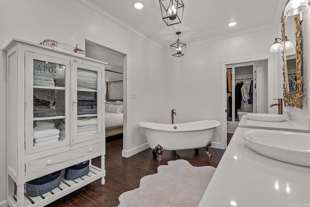 bathroom featuring a bathtub, wood-type flooring, ornamental molding, and vanity