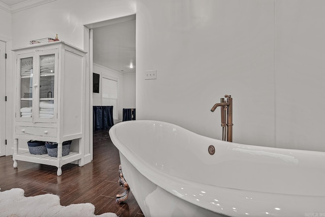 bathroom featuring wood-type flooring, crown molding, a bathing tub, and sink