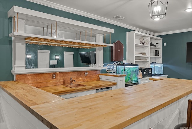 kitchen with butcher block counters, crown molding, sink, and pendant lighting