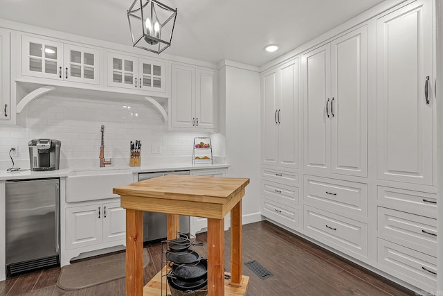 kitchen featuring backsplash, sink, decorative light fixtures, dark hardwood / wood-style floors, and white cabinetry