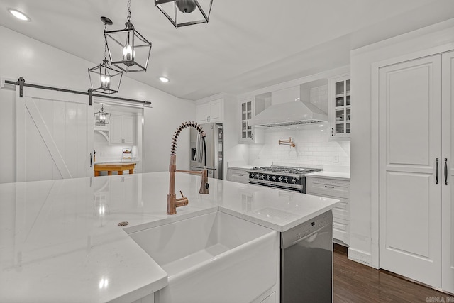 kitchen featuring a barn door, pendant lighting, white cabinets, custom exhaust hood, and appliances with stainless steel finishes