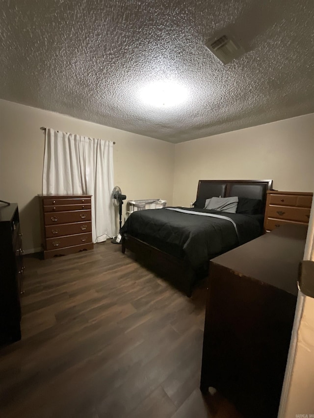 bedroom featuring dark hardwood / wood-style flooring and a textured ceiling